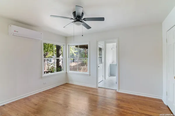 a view of an empty room with a window and wooden floor
