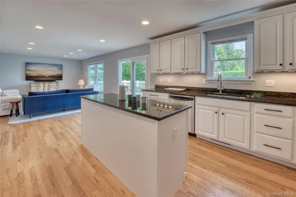 a kitchen with granite countertop a stove a sink dishwasher and a refrigerator with wooden floor