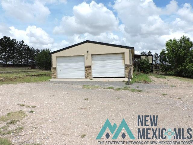 35 Mays Road Clayton, NM 88415 - Photo 6 of 31 Two-car garage with two white roll-up doors, tan stucco exterior, and stone veneer accents
