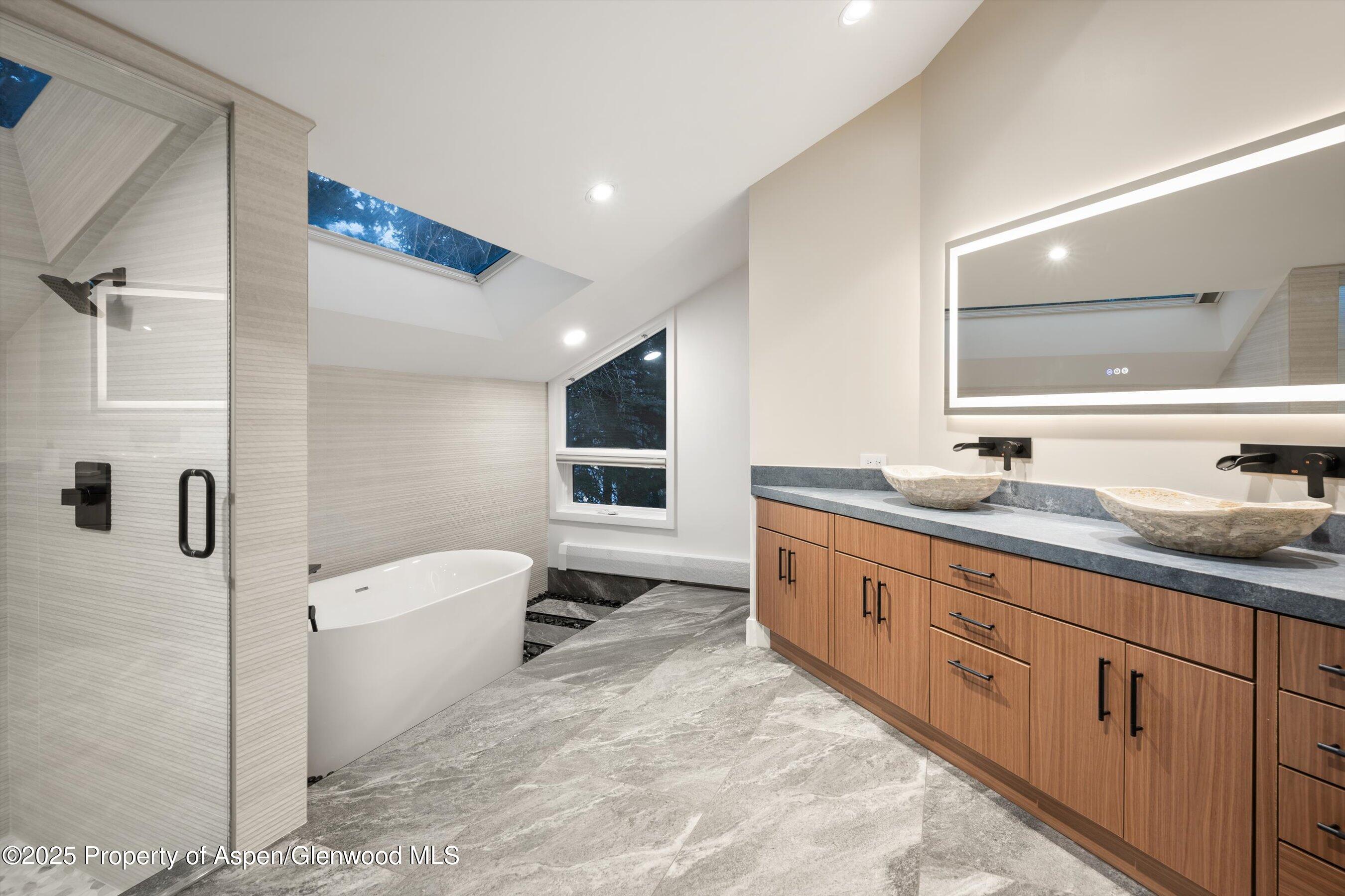 75 Bennett Court Aspen, CO 81611 - Photo 24 of 65 a spacious bathroom with a double vanity sink a mirror and a bathtub