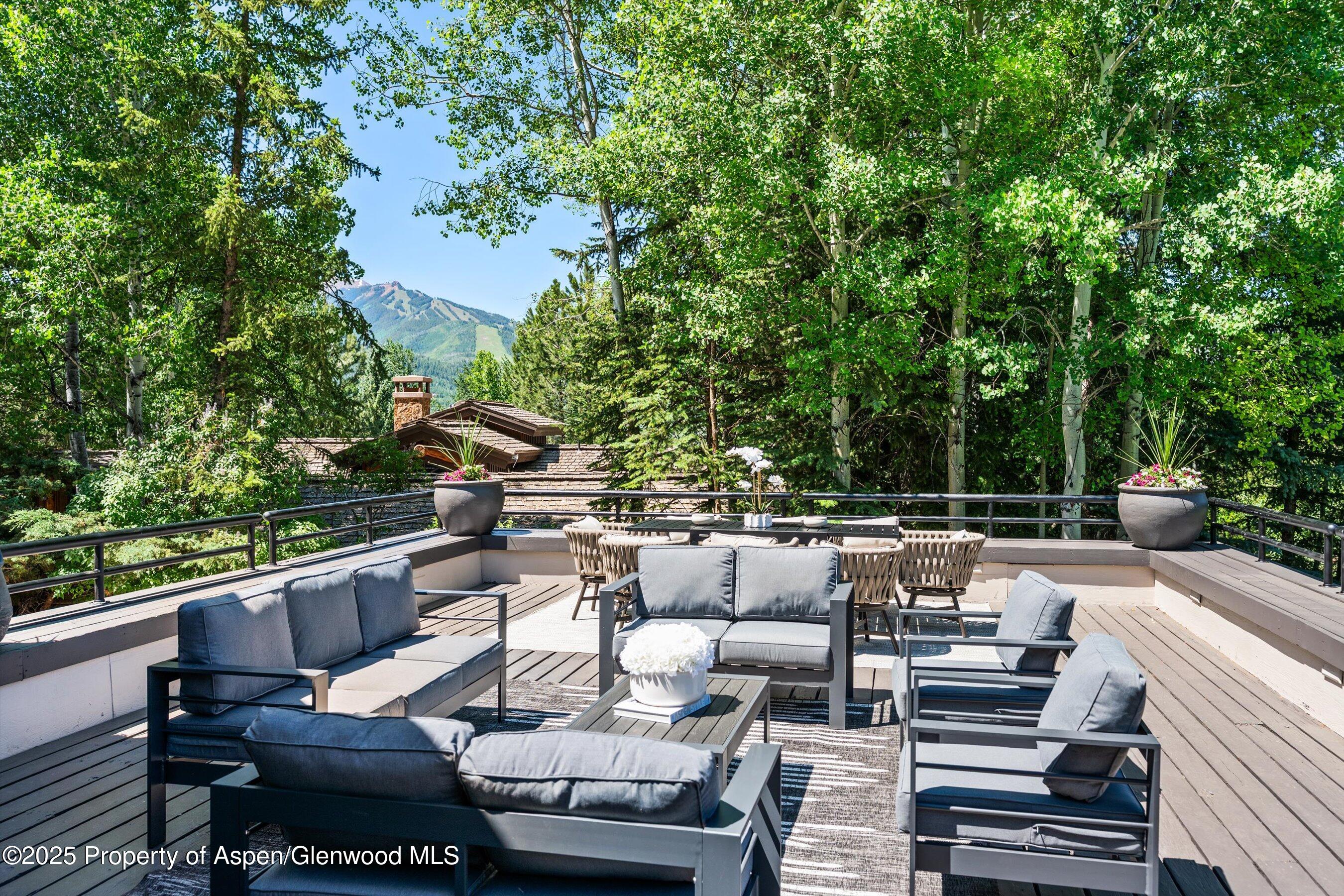 75 Bennett Court Aspen, CO 81611 - Photo 41 of 65 a view of a patio with couches table and chairs with potted plants and large trees