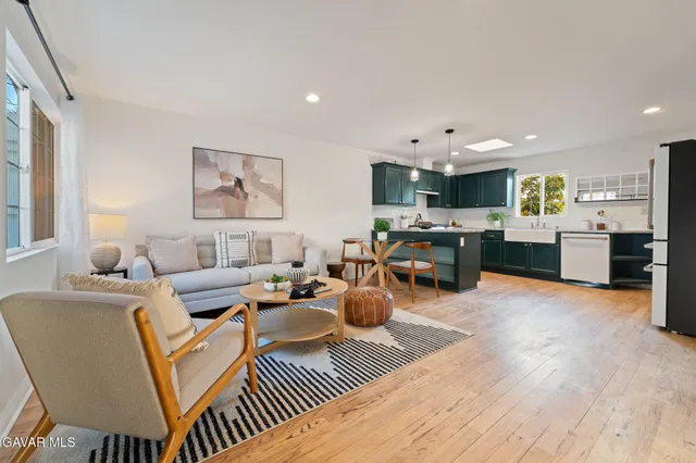 a living room with furniture kitchen view and a wooden floor