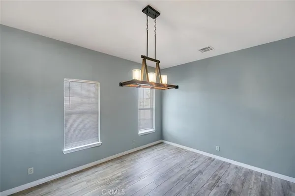 a view of an empty room with wooden floor fireplace and a window