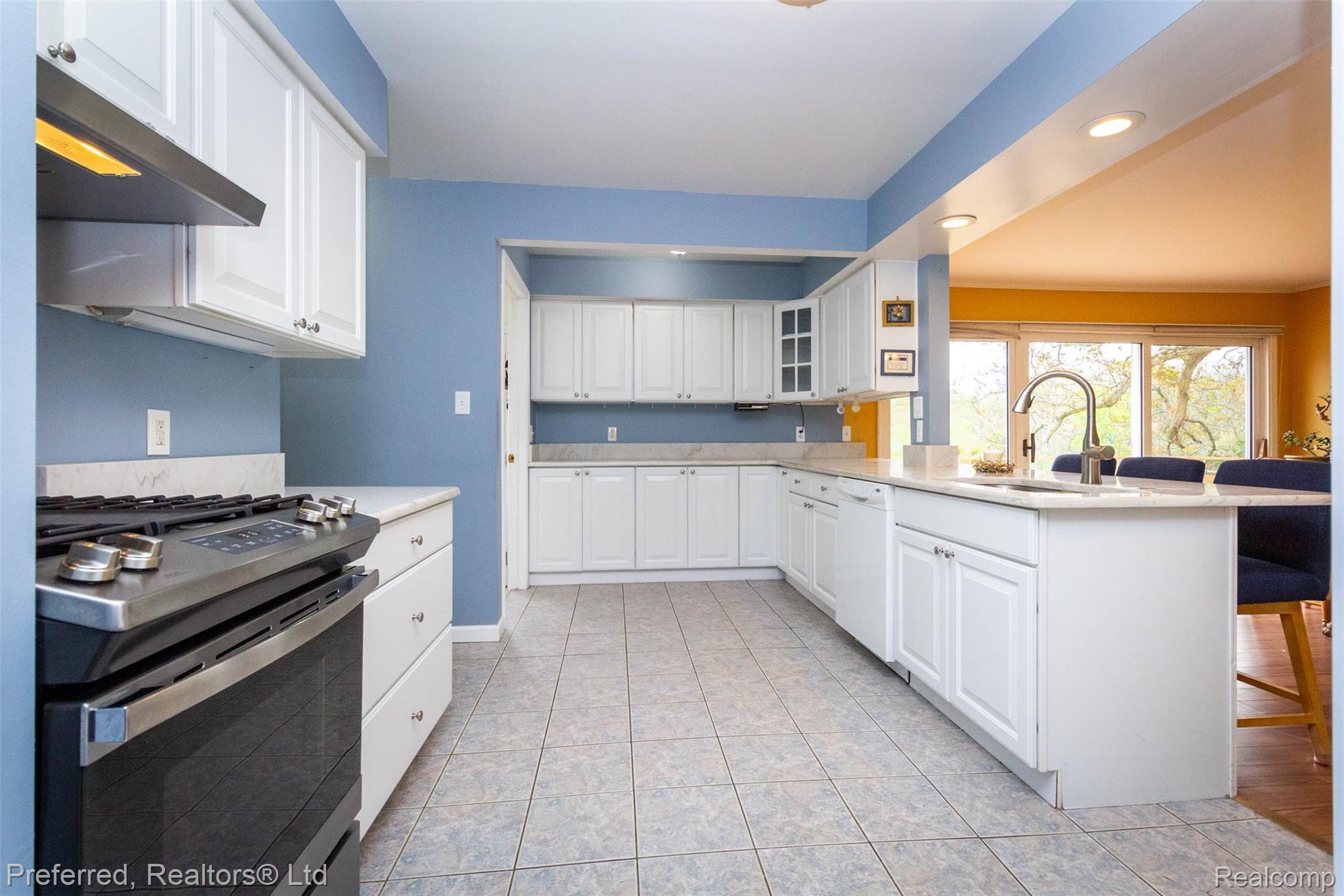 9840 Currie Road Northville, MI 48167 - Photo 15 of 62 Kitchen with a kitchen breakfast bar, stainless steel gas stove, a peninsula, white cabinetry, and glass fronted cabinets
