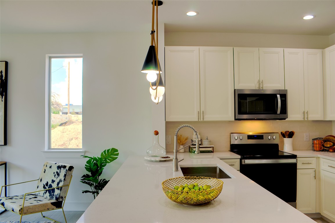 304 Tesla Circle Austin, TX 78681 - Photo 5 of 38 Kitchen with electric stove, backsplash, stainless steel microwave, white cabinetry, and recessed lighting