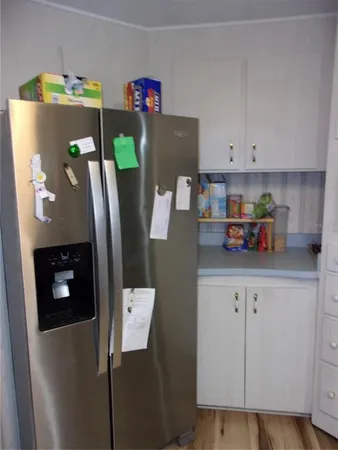 a sign board with flower plants and large trees