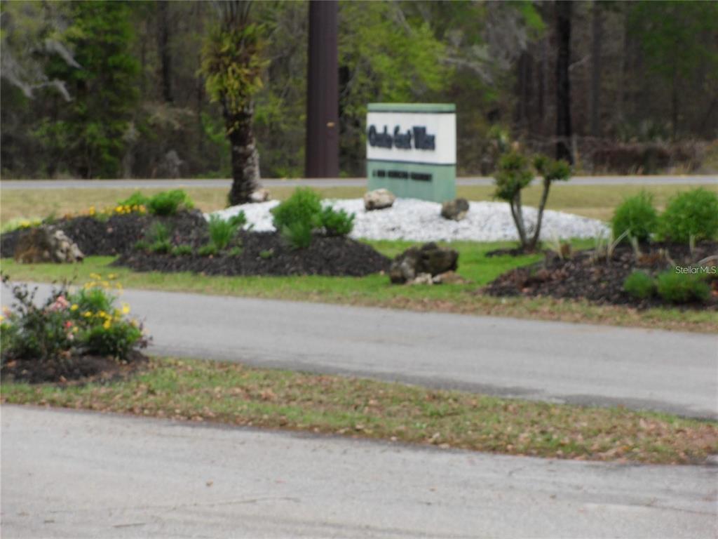 6485 Northeast 2nd Street Ocala, FL 34470 - Photo 47 of 55 a sign board with flower plants and large trees