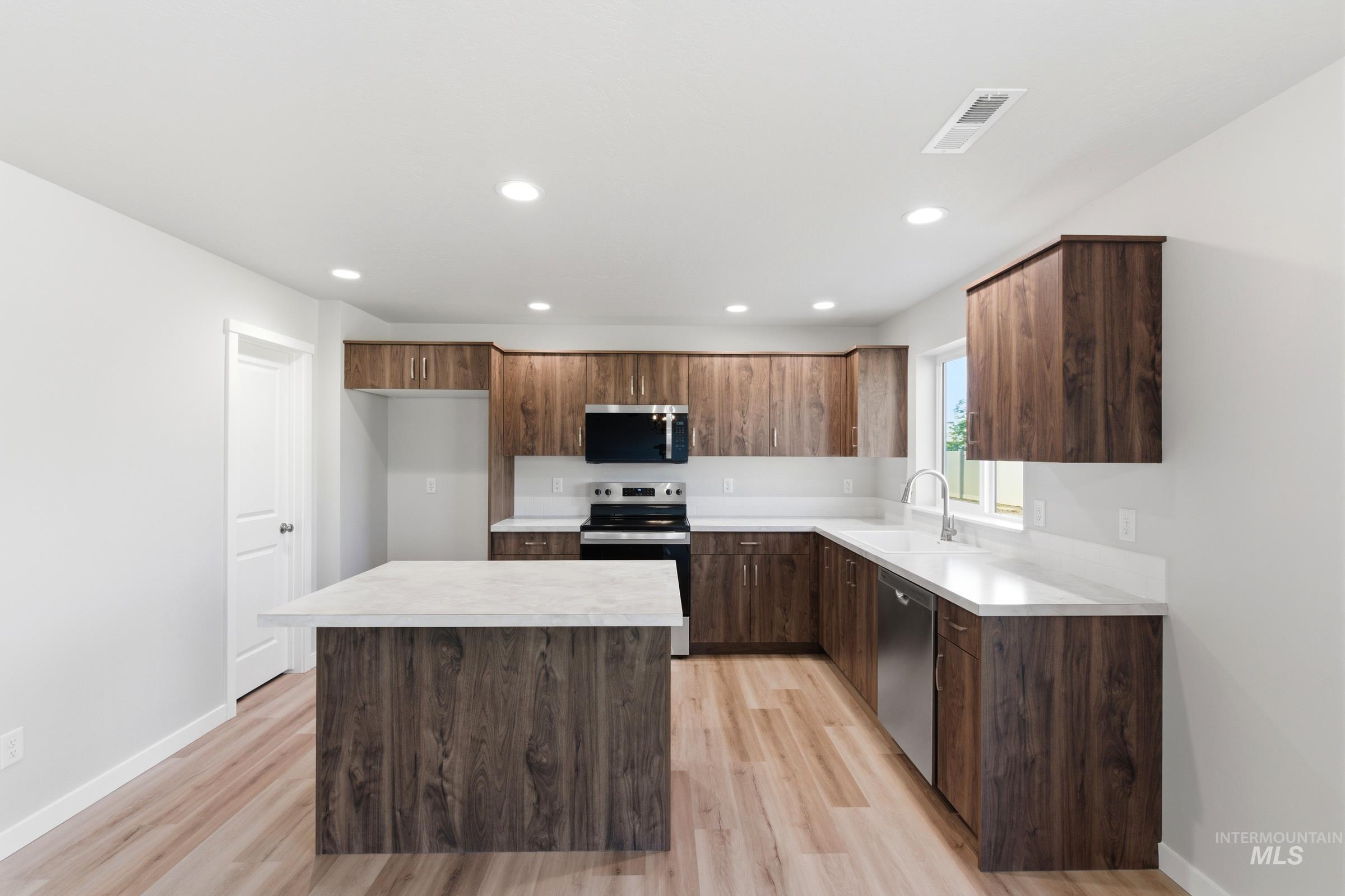 13709 Redway Court Caldwell, ID 83607 - Photo 3 of 28 Modern kitchen featuring wood-finish cabinetry, light-toned countertops, and stainless steel appliances