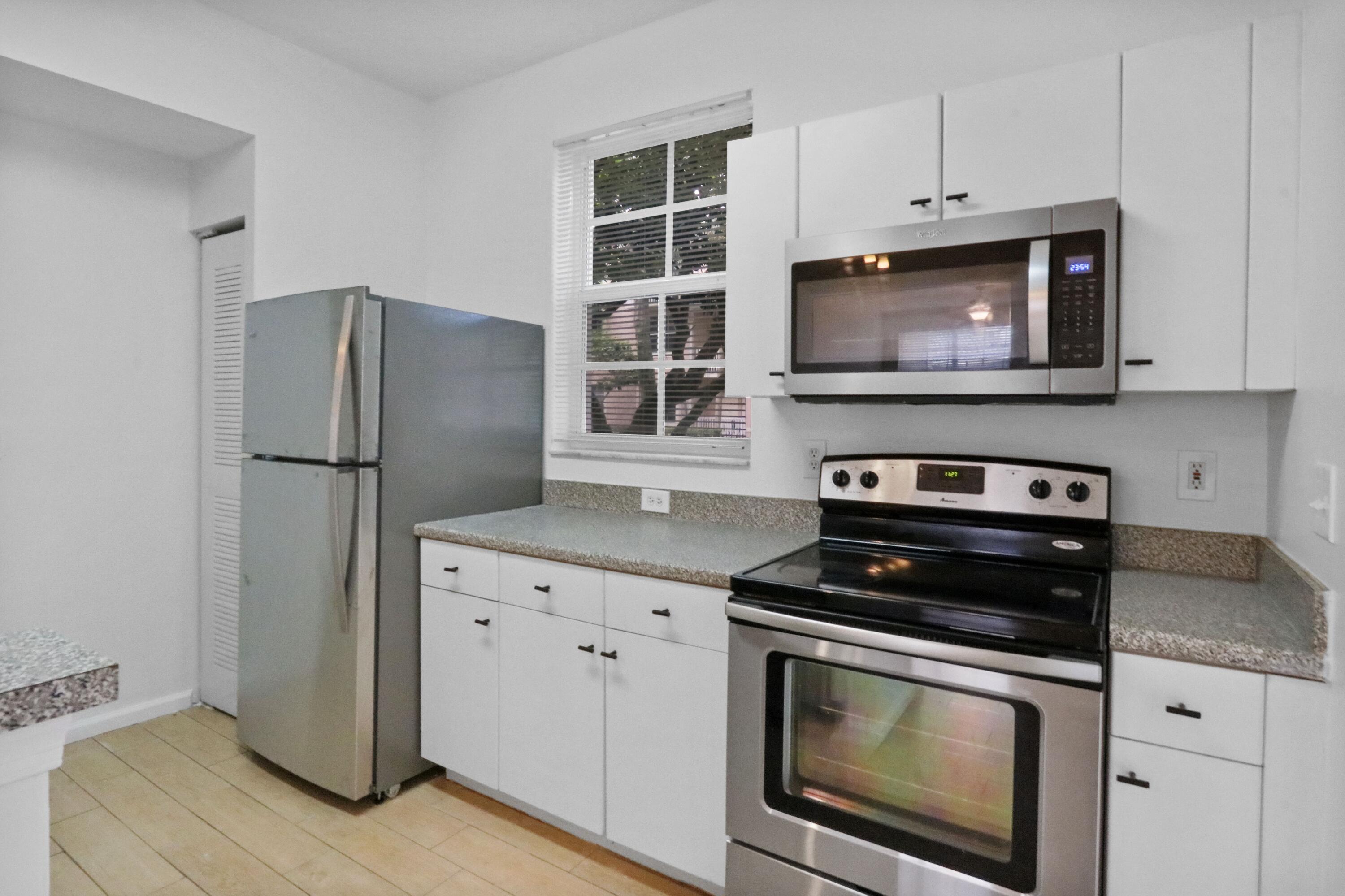 4784 Central Boulevard, Unit 10 Jupiter, FL 33458 - Photo 11 of 29 a kitchen with cabinets stainless steel appliances and a wooden floor