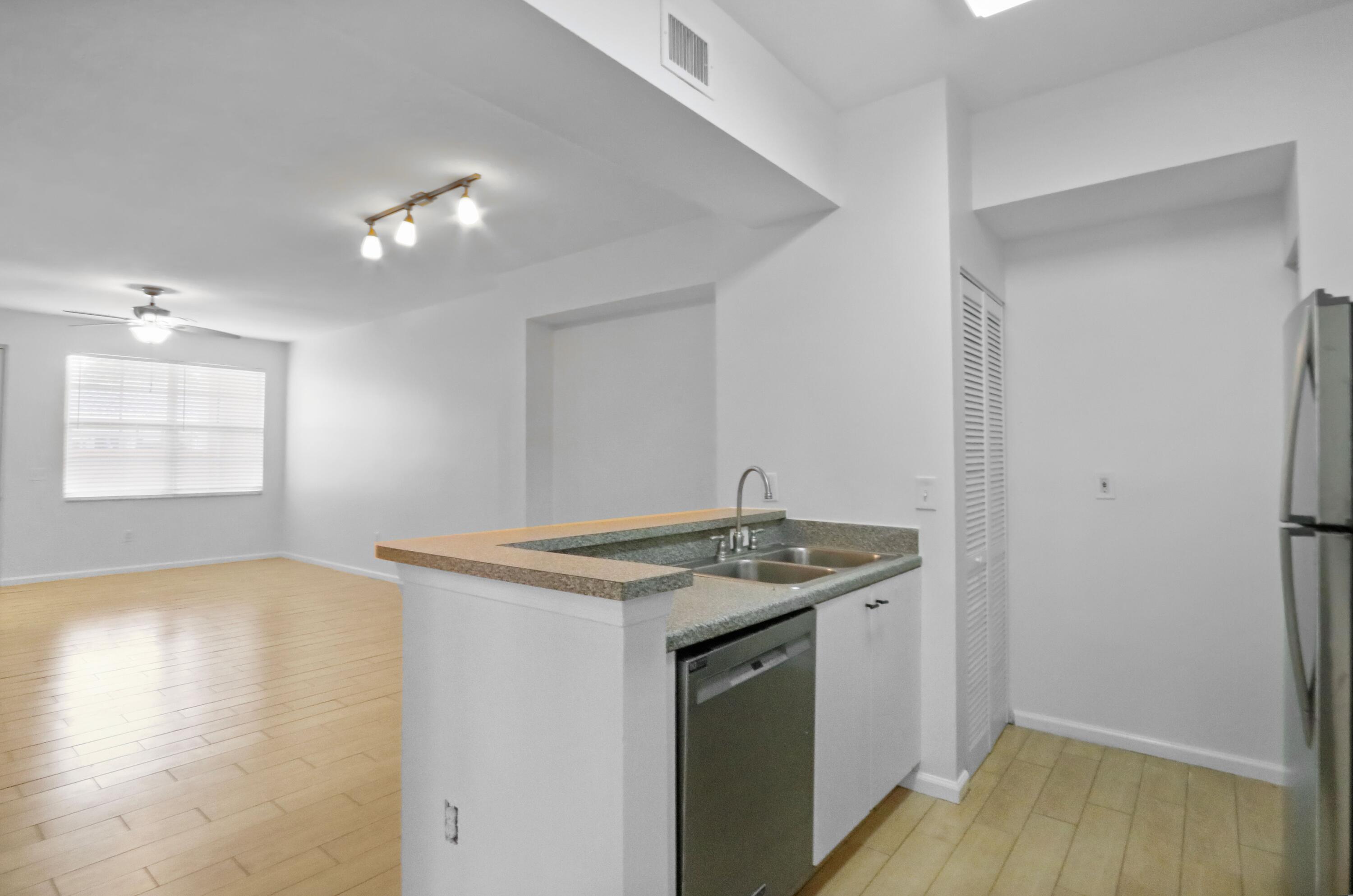 4784 Central Boulevard, Unit 10 Jupiter, FL 33458 - Photo 13 of 29 a view of a kitchen that shows a sink dishwasher and wooden floor