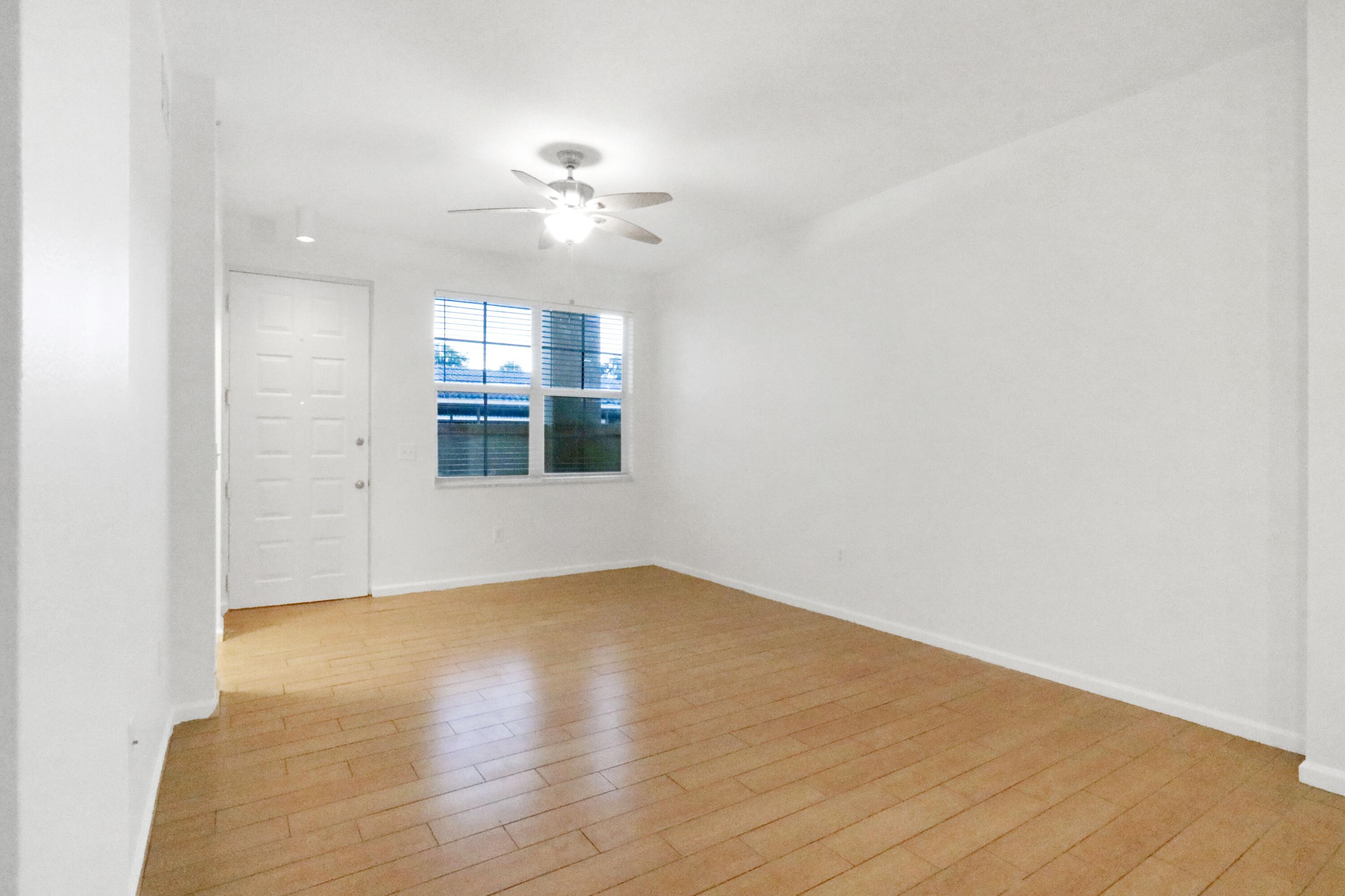 4784 Central Boulevard, Unit 10 Jupiter, FL 33458 - Photo 5 of 29 an empty room with wooden floor chandelier fan and windows