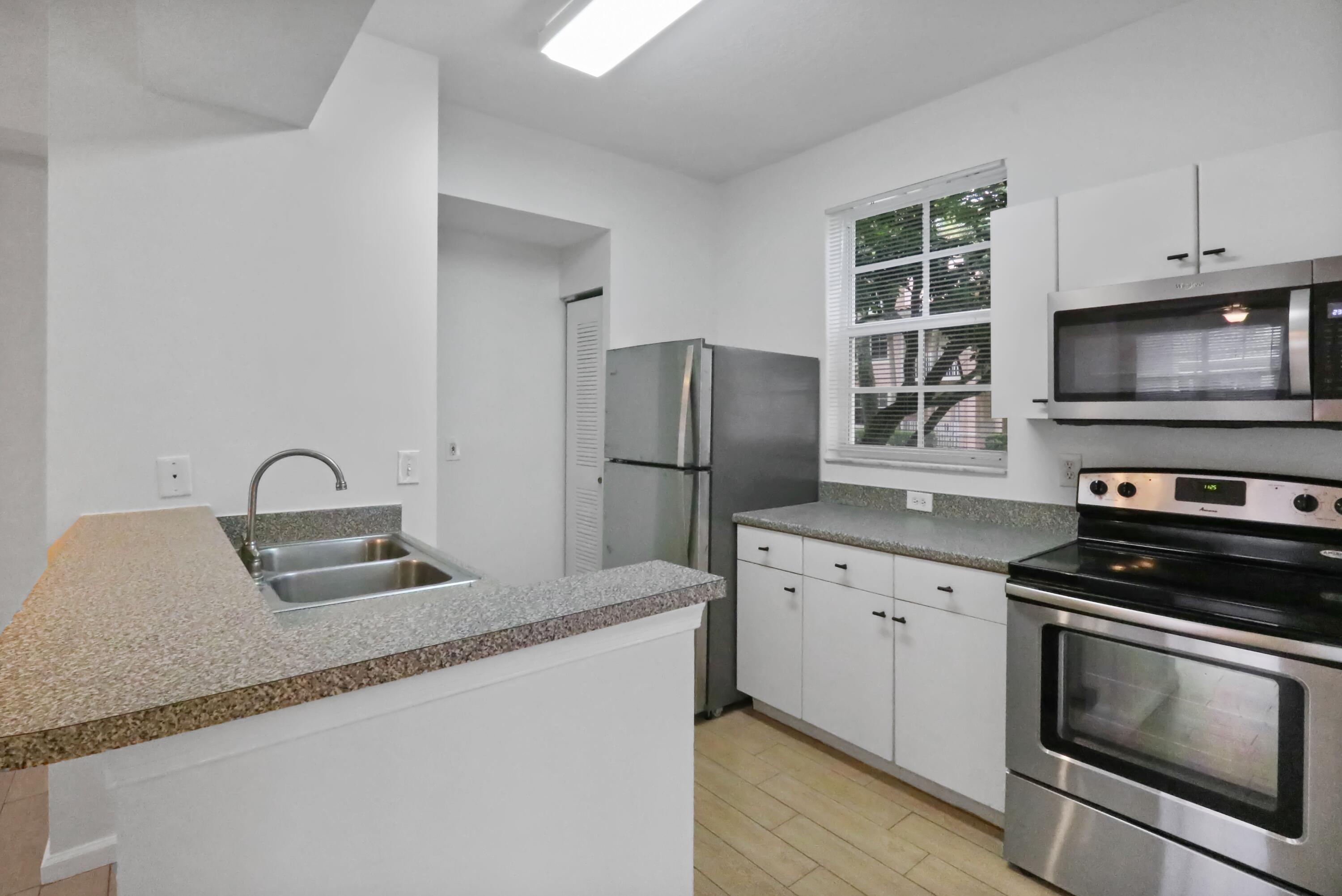 4784 Central Boulevard, Unit 10 Jupiter, FL 33458 - Photo 10 of 29 a kitchen with granite countertop a sink stove and refrigerator