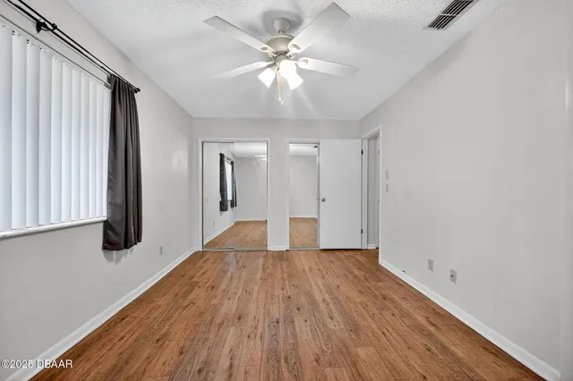 a view of a room with wooden floor and a ceiling fan