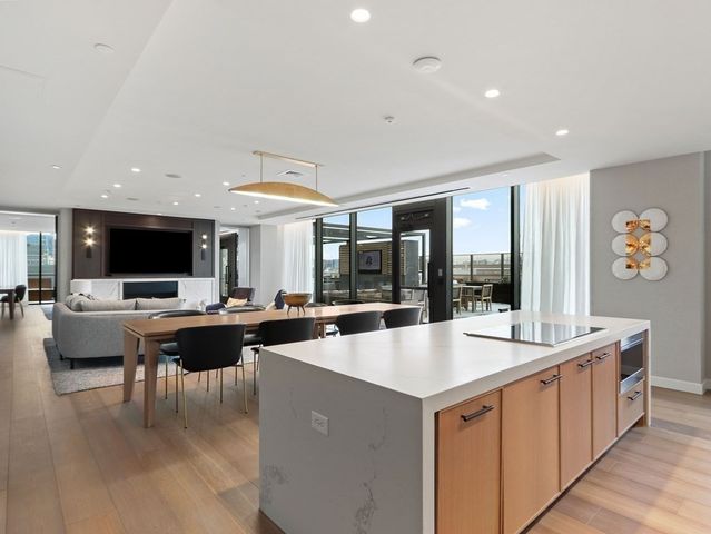 a living room with stainless steel appliances kitchen island granite countertop a sink and a large window