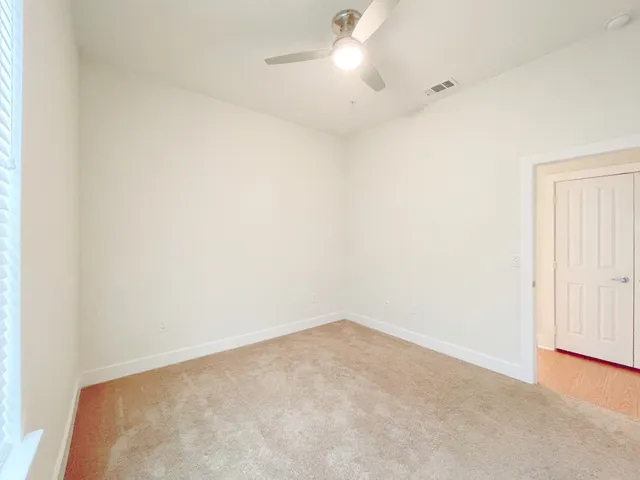 an empty room with a fan & a window