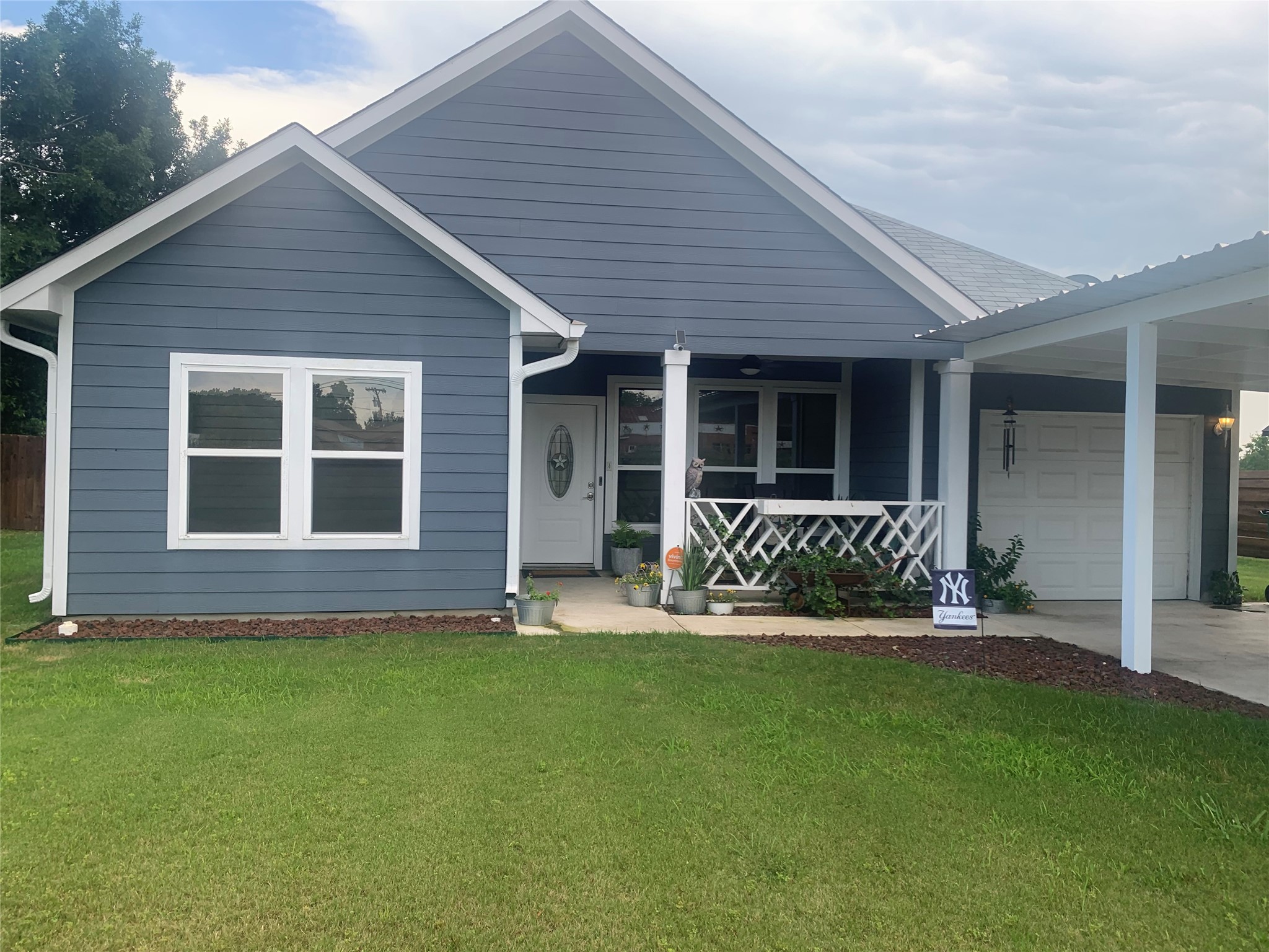 View of front of home with a front yard, a porch, and a garage