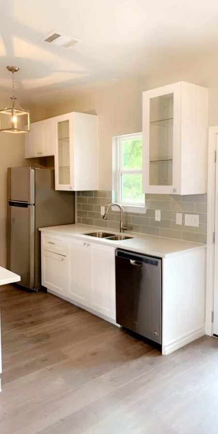 307 West Front Street Thorndale, TX 76577 - Photo 24 of 27 Kitchen with glass insert cabinets, white cabinets, appliances with stainless steel finishes, hanging light fixtures, and tasteful backsplash