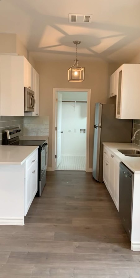 307 West Front Street Thorndale, TX 76577 - Photo 25 of 27 Kitchen with decorative backsplash, stainless steel appliances, white cabinetry, and light wood-type flooring