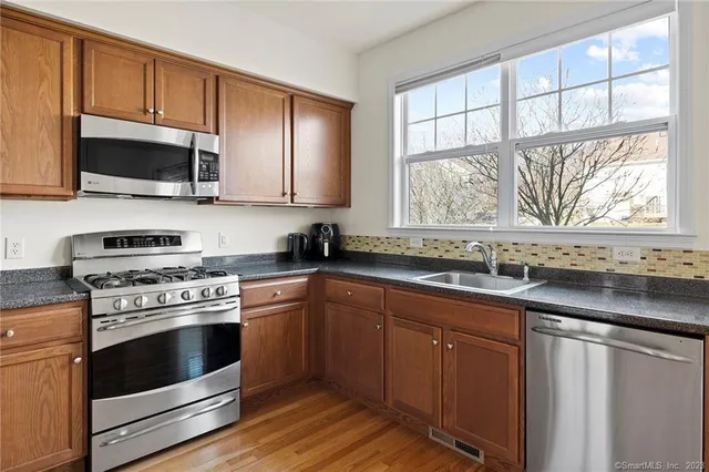 a kitchen with stainless steel appliances granite countertop a stove a sink and a microwave