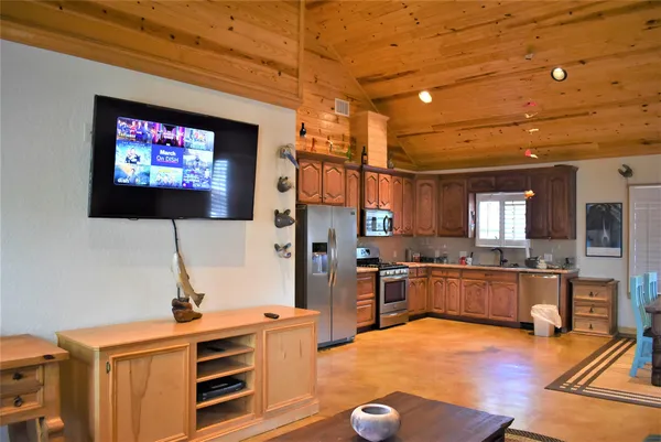 a living room with stainless steel appliances furniture and a flat screen tv