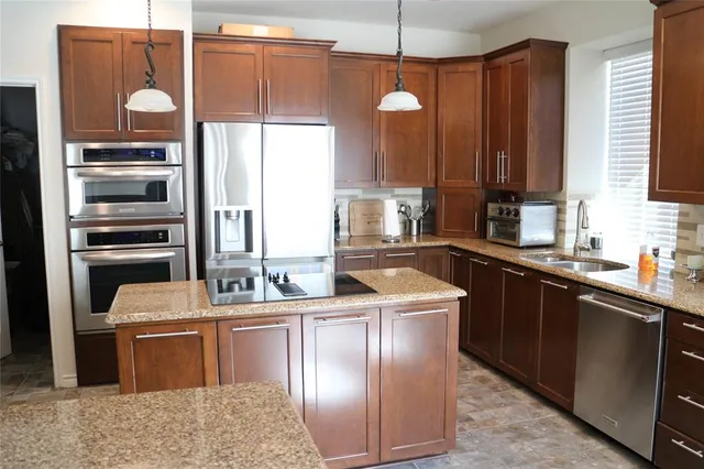 a kitchen with stainless steel appliances granite countertop a sink a stove and a refrigerator