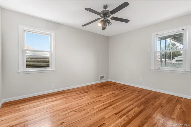 a view of empty room with wooden floor and fan