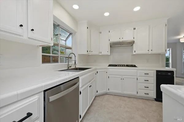 a kitchen with granite countertop white cabinets white stainless steel appliances and a sink