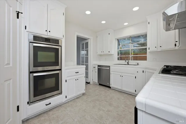 a kitchen with stainless steel appliances white cabinets and a stove top oven