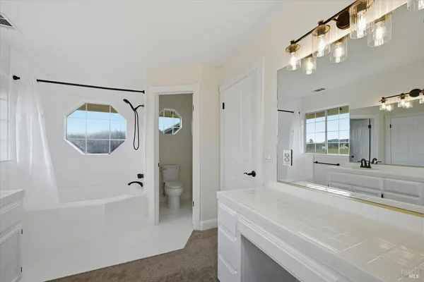 a spacious bathroom with a tub shower and mirror