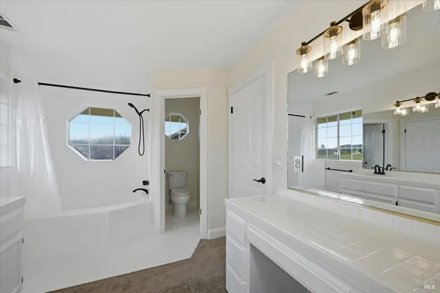 a spacious bathroom with a tub shower and mirror