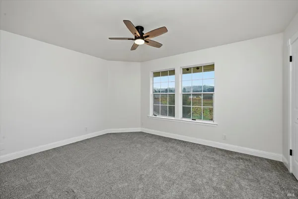an empty room with a ceiling fan and window