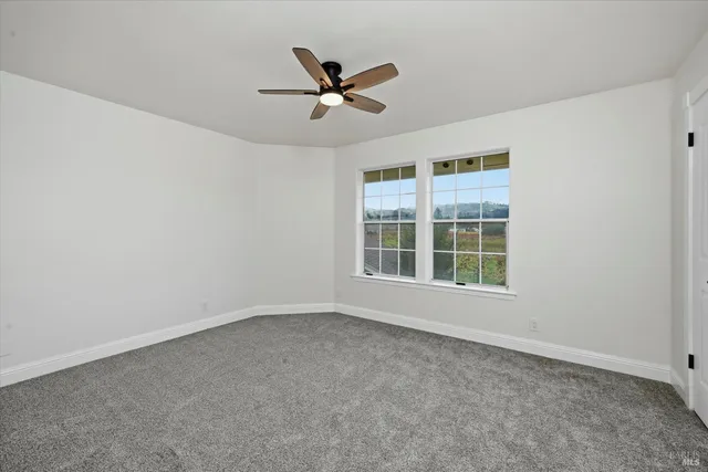 an empty room with a ceiling fan and window