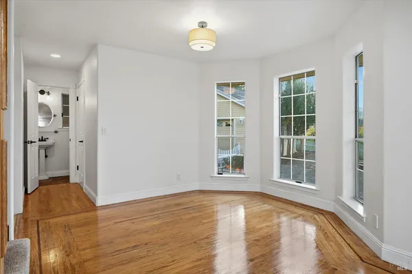 a view of an empty room with wooden floor fireplace and a window