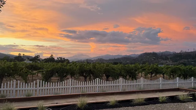 a view of a green field with wooden fence