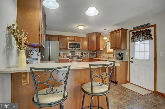 a kitchen with stainless steel appliances granite countertop a table chairs and a refrigerator