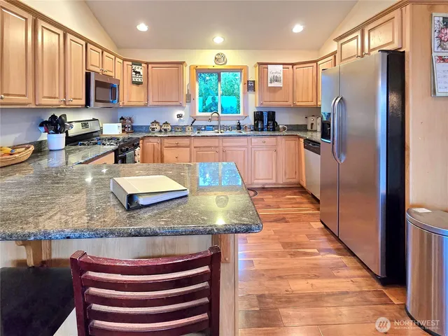 a kitchen with stainless steel appliances granite countertop a refrigerator a stove and a sink