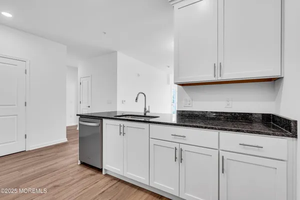 a kitchen with granite countertop white cabinets and a sink