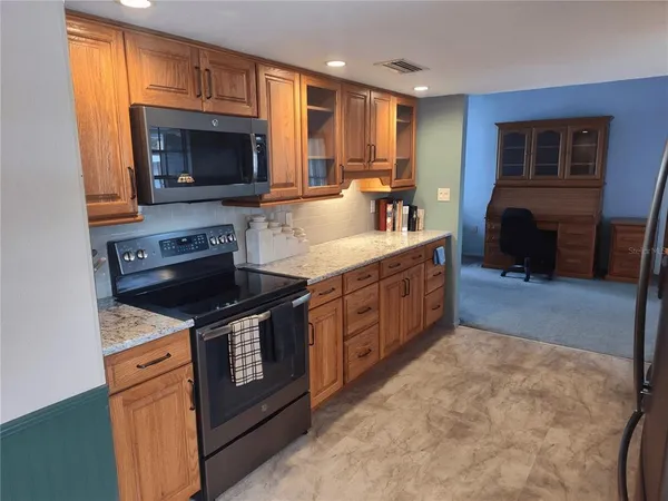 a kitchen with stainless steel appliances granite countertop a stove a sink and a microwave