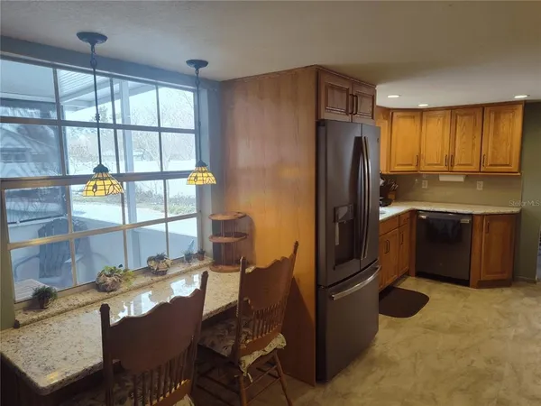 a kitchen with stainless steel appliances granite countertop a refrigerator a stove a sink a dining table and chairs with wooden floor