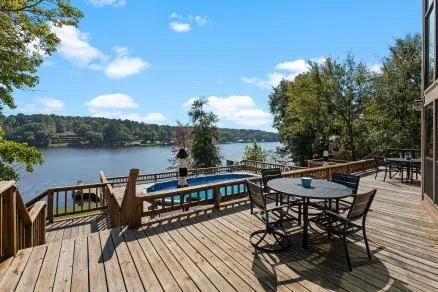 a view of a roof deck with table and chairs a barbeque with wooden floor and plants