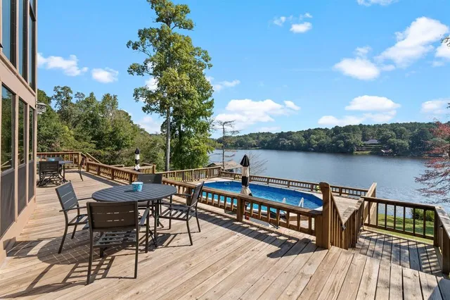 a view of a roof deck with table and chairs a barbeque with wooden floor and fence