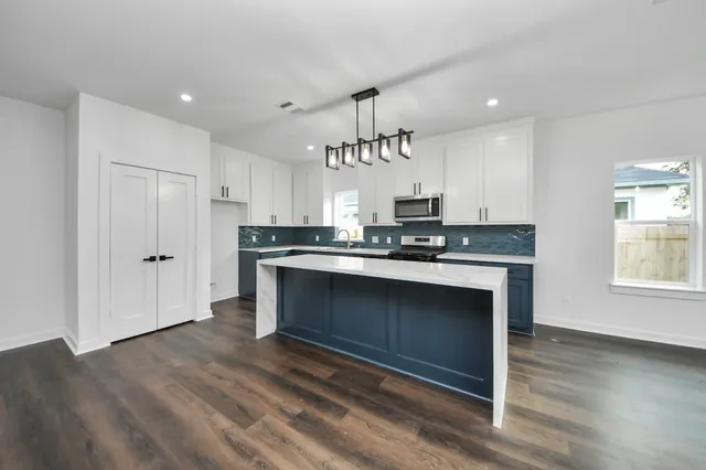 a large kitchen with a center island wooden floor and stainless steel appliances
