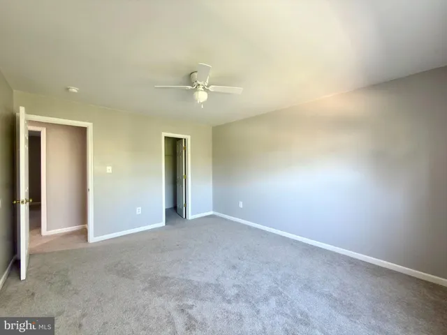 an empty room with a window and a ceiling fan