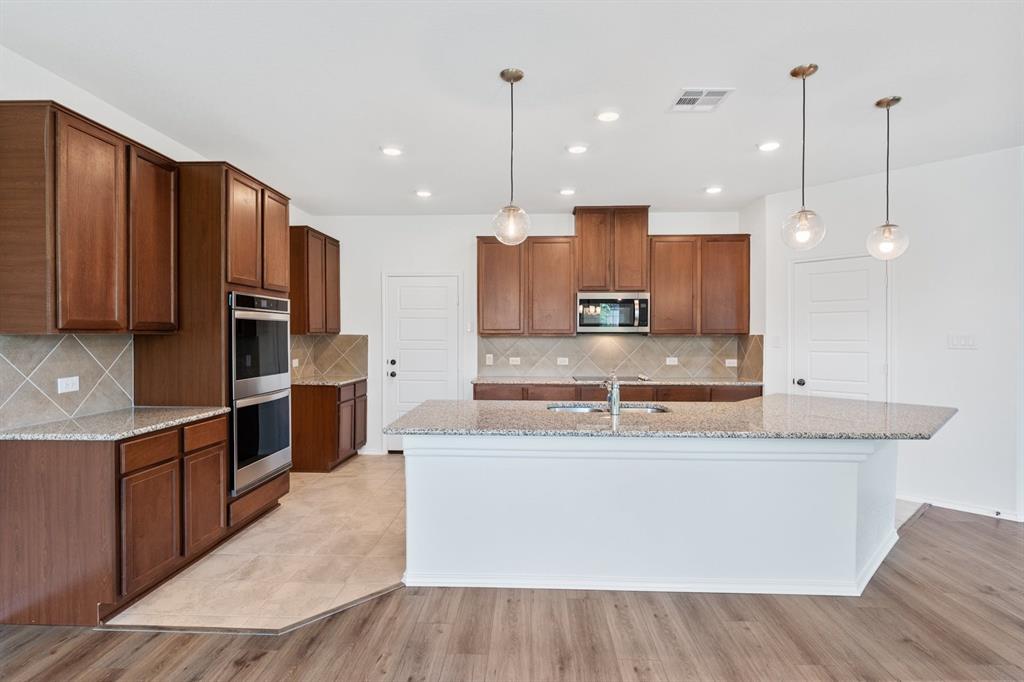 210 McGinnis Trail Kyle, TX 78640 - Photo 3 of 10 a large kitchen with stainless steel appliances kitchen island a large island in the center