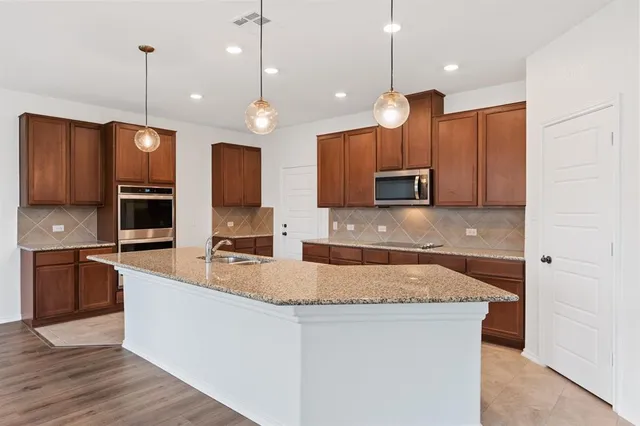 a large kitchen with stainless steel appliances kitchen island granite countertop a stove a sink and a microwave