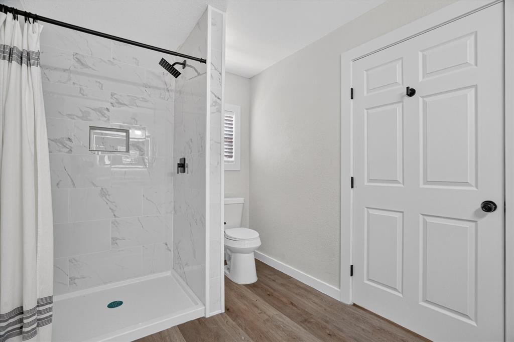 795 Meadow Road Springtown, TX 76082 - Photo 12 of 25 Shower with marble-look tile, matte black fixtures, and built-in niche