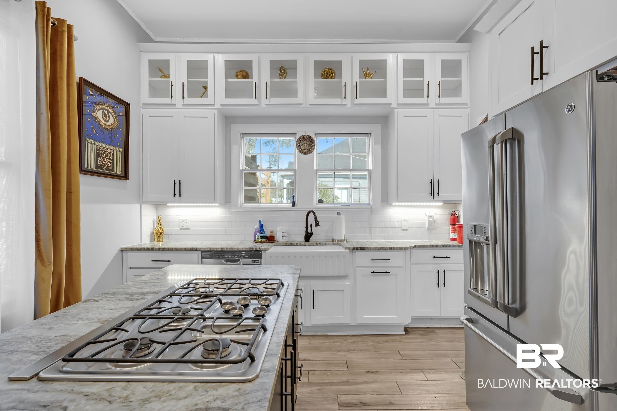 1322 Dauphin Street Mobile, AL 36604 - Photo 12 of 21 Kitchen featuring white cabinets, stainless steel appliances, glass insert cabinets, light stone countertops, and light wood-type flooring