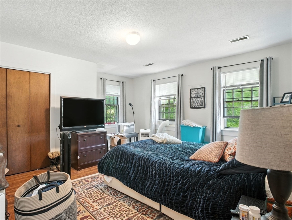 167 Warren Wright Road Belchertown, MA 01007 - Photo 26 of 42 a bedroom with a bed a couch and a flat screen tv