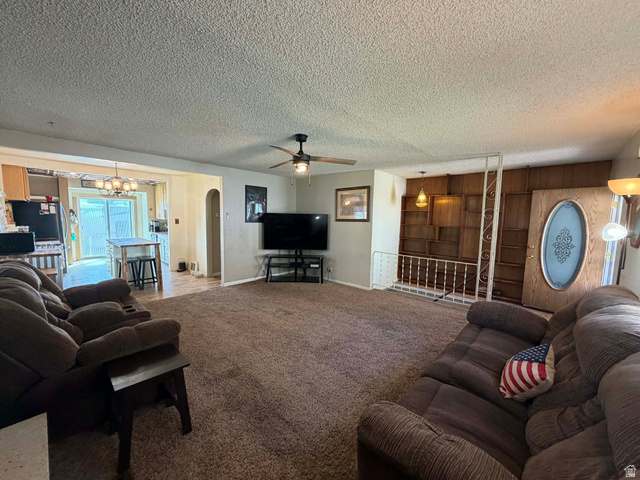 156 D Street Helper, UT 84526 - Photo 8 of 24 Carpeted living area featuring arched walkways, a textured ceiling, a ceiling fan, a chandelier, and wood walls