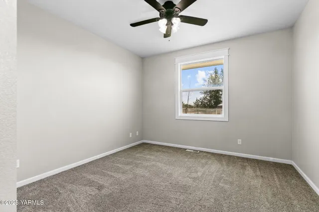 an empty room with a window and a fan